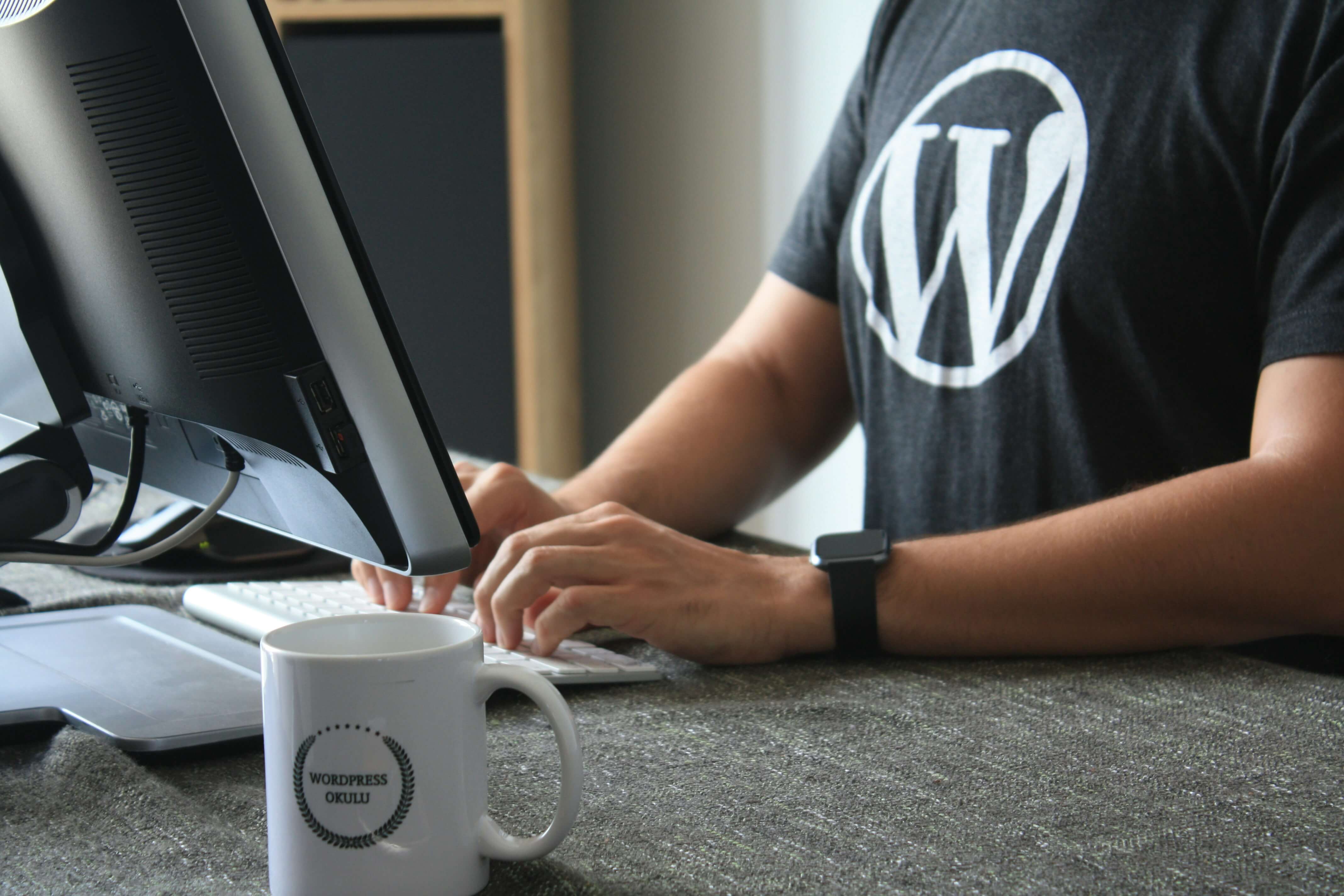 persoon met wordpress t-shirt is met computer bezig